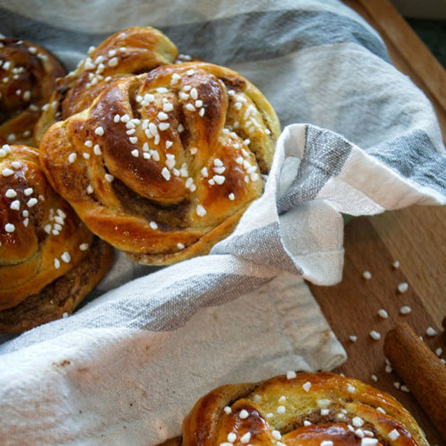 Frisch gebackene Hefeschnecken mit Hagelzucker in einem Tuch auf einem Holztisch